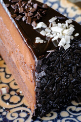 A decadent chocolate cake richly layered and generously adorned with chocolate shavings and sprinkles