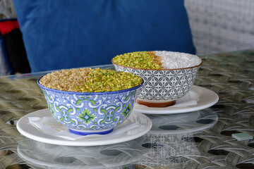 Two bowls of dessert topped with nuts and pistachios