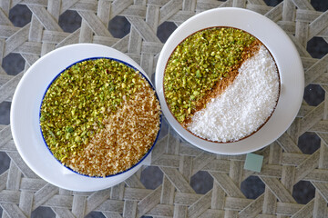 Two delectable desserts one topped with pistachios and nuts the other with coconut and nuts