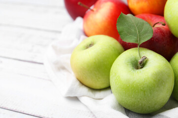 Different whole ripe apples on white wooden table, closeup. Space for text