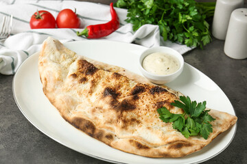 Delicious calzone served with sauce on grey table, closeup
