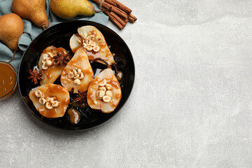Delicious pears with caramel sauce, nuts and spices on grey table, top view. Space for text