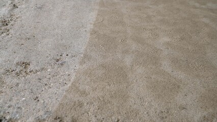 Worker cleaning concrete surface with high pressure washer leaving diagonal stripes