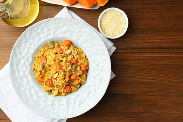 Delicious pumpkin risotto on wooden table, flat lay