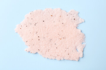Sample of body scrub on light blue background, top view. Skin care