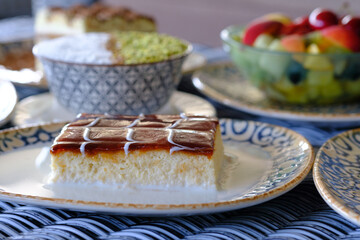 A delectable slice of creamy custard cake topped with a rich caramel glaze sits on a patterned plate
