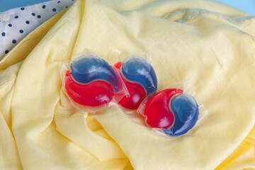 Laundry detergent capsules on clean clothes, closeup