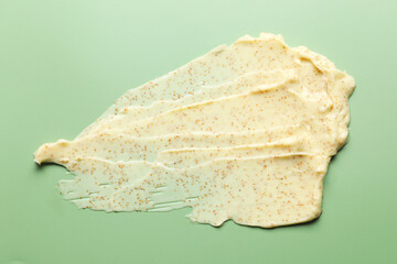 Smear of body scrub on light green background, top view