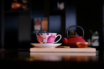 Floral teacup and teapot set on a wooden board ready for a relaxing moment