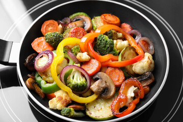 Frying pan with mix of vegetables and mushrooms on cooktop, closeup