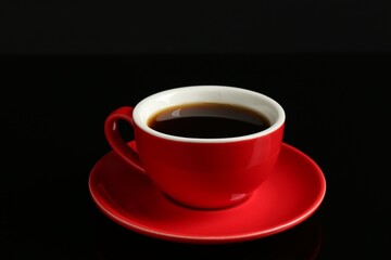 Red cup with coffee on black background, closeup