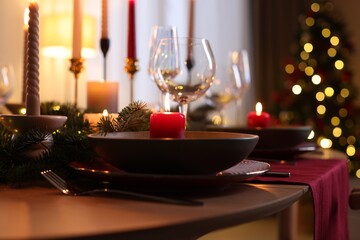Festive table setting in room decorated for Christmas, closeup. Bokeh effect