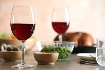 Red wine and delicious dinner served on wooden table, closeup