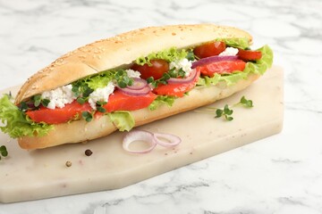 Delicious baguette with salmon on white marble table, closeup
