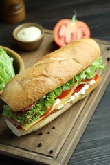 Delicious baguette sandwich with salami and cheese on grey wooden table