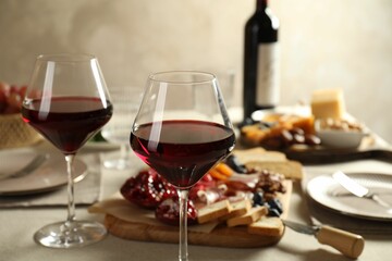Red wine and different snacks served on table, closeup