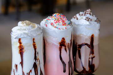 Three creamy frozen drinks topped with whipped cream and chocolate sauce