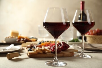 Red wine and different snacks served on light grey table