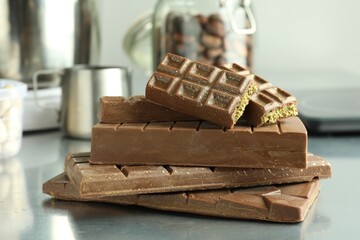 Stack of tasty Dubai chocolate bars with pistachios and knafeh on grey table, closeup