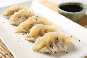 Delicious gyoza dumplings with sesame seeds served on table, closeup