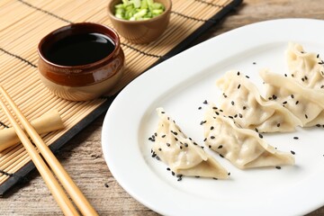 Delicious gyoza dumplings with sesame seeds served on wooden table, closeup