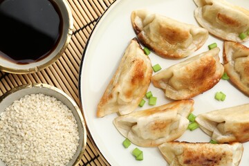 Delicious fried gyoza dumplings with green onions served on table, flat lay