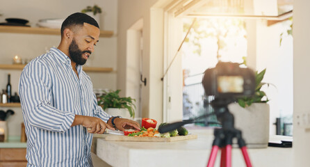 Camera, live streaming and man in kitchen for cooking tutorial, cuisine and meal preparation in home. Culinary influencer, content creator and person with food, recipe or ingredients for social media