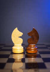 chess pieces of knights on a chessboard on a dark background. © ketrin