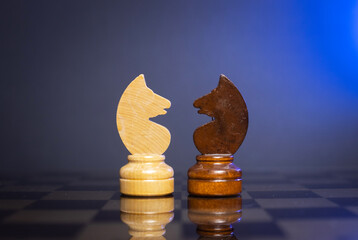 chess pieces of knights on a chessboard on a dark background.