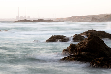 Long exposure of ocean waves crashing against rocks in Porto Covo, Portugal