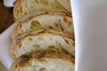 Slices of crusty artisan bread light and airy inside resting on a white linen cloth