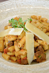 A delectable pasta dish featuring penne pasta in a rich tomato sauce topped with shaved cheese and fresh herbs
