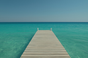 Obraz premium Tranquil wooden dock extending into clear turquoise water on a sunny day