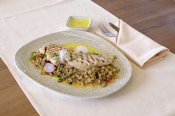 Grilled chicken breast served atop a barley and vegetable medley drizzled with a creamy sauce