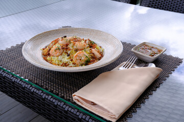 Shrimp and rice dish served on a table with a side of sauce