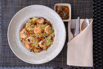 Aromatic shrimp and rice dish garnished with fried onions served with a vibrant dipping sauce