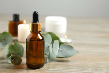 Eucalyptus essential oil in a glass bottle with green eucalyptus leaves on a wooden background. Aromatherapy concept. Spa. Natural organic ingredients for cosmetics and body care.