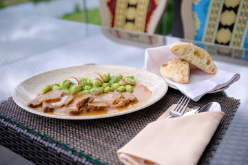 Sliced roasted meat with creamy herb sauce and dumplings served outdoors