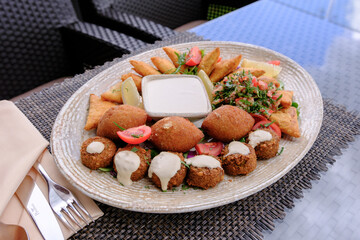 A platter of assorted Middle Eastern appetizers including fried pastries kibbeh falafel and a creamy dip