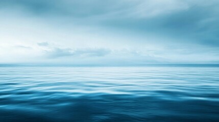 Obraz premium This image showcases a vast expanse of serene blue ocean water, featuring gentle waves under a softly cloudy sky, evoking a sense of tranquility and peace.