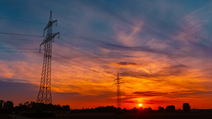 Summer sunset with a dramatic sky and overland high voltage lines near Tabertshausen, Aholming, Deggendorf, Bavaria, Germany