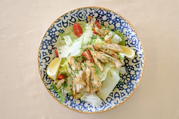 Grilled chicken salad with romaine lettuce parmesan cheese cherry tomatoes and lemon wedges