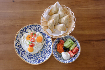 A delicious and healthy breakfast featuring fried eggs pastries and a fresh vegetable side