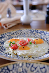 Sunny side up eggs garnished with fresh tomatoes and microgreens