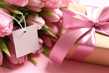 Beautiful pink tulips and craft gift with paper card on colored background