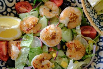 Shrimp salad with fresh vegetables and a lemon wedge