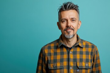 Fototapeta premium Confident Middle-Aged Man in Plaid Shirt Against a Turquoise Background