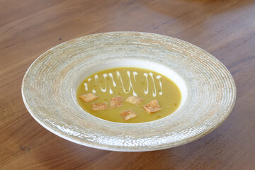 Creamy soup garnished with crispy croutons and a swirl of cream served in a stylish bowl