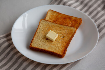 Homemade Toasted Bread Slice with Butter on a Plate, side view.
