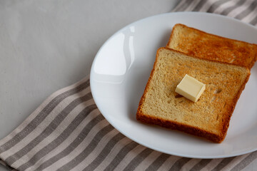Homemade Toasted Bread Slice with Butter on a Plate, side view.